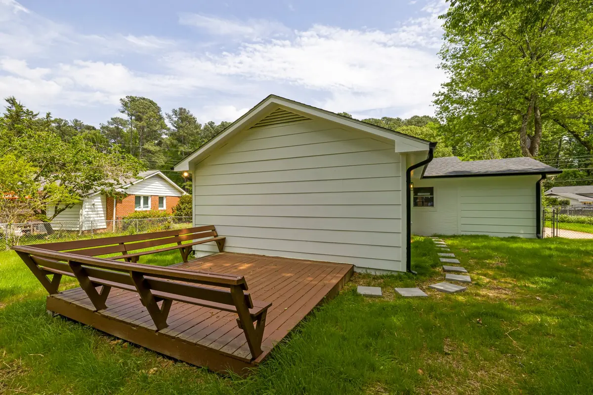 Backyard deck and lawn bordered by trees, a mosquito, flea, and tick treatment area