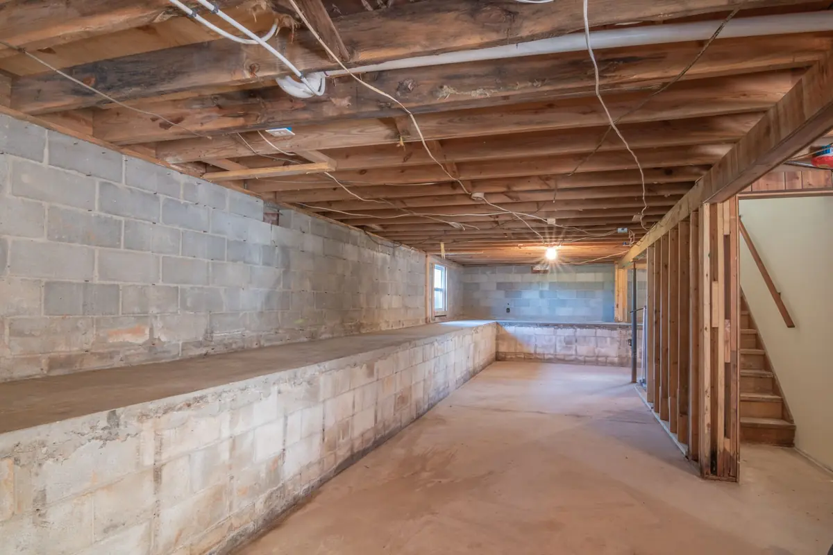 Unfinished basement with block foundation walls and exposed wood joists