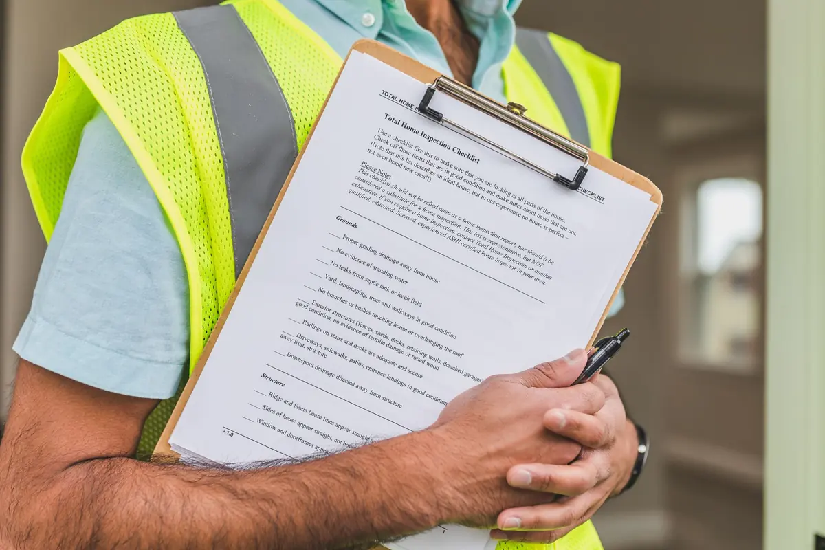 Inspector holding a home inspection checklist on a clipboard