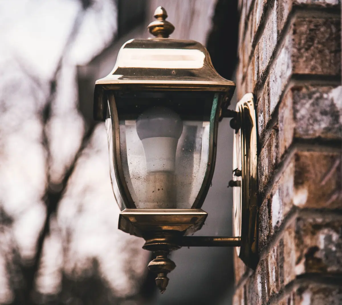Outdoor porch lantern on a brick wall, a light that draws insects and the spiders that hunt them