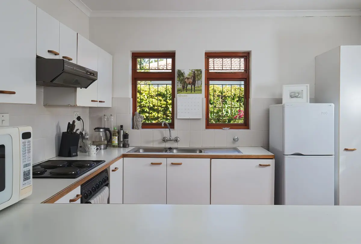 White kitchen with sink, stove, and refrigerator, the primary cockroach treatment area